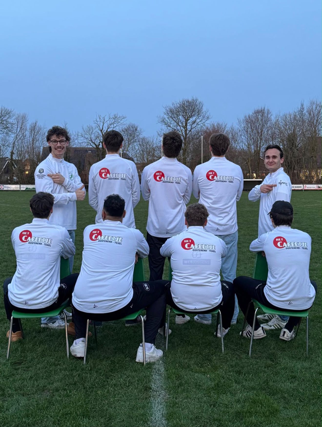 Spelers van SV Oosterend wijzen naar TX en De Rommelpot op de schouders van het witte clubshirt